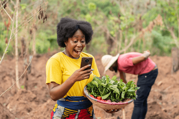 A woman outdoors checking a verification code on her phone.